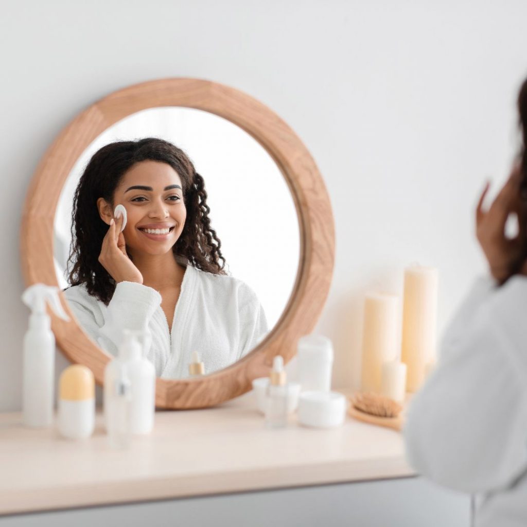 Femme massant son visage avec une huile démaquillante, soin du soir douceur